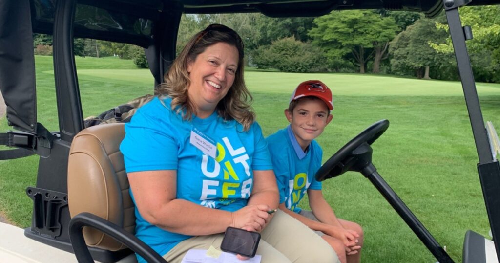 Volunteers in golf cart at Habitat Capital Region Home-in-One Golf Outing