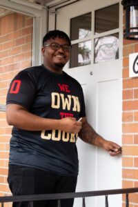 De'Angelo smiles at the camera before unlocking the front door.