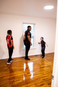 Jaedyn, De'Angelo, and Jordan explore the inside of their home while looking out a window.