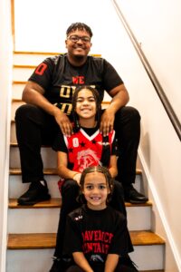 De'Angelo, Jaedyn, and Jordan pose for a photo on the stairs inside their new house.
