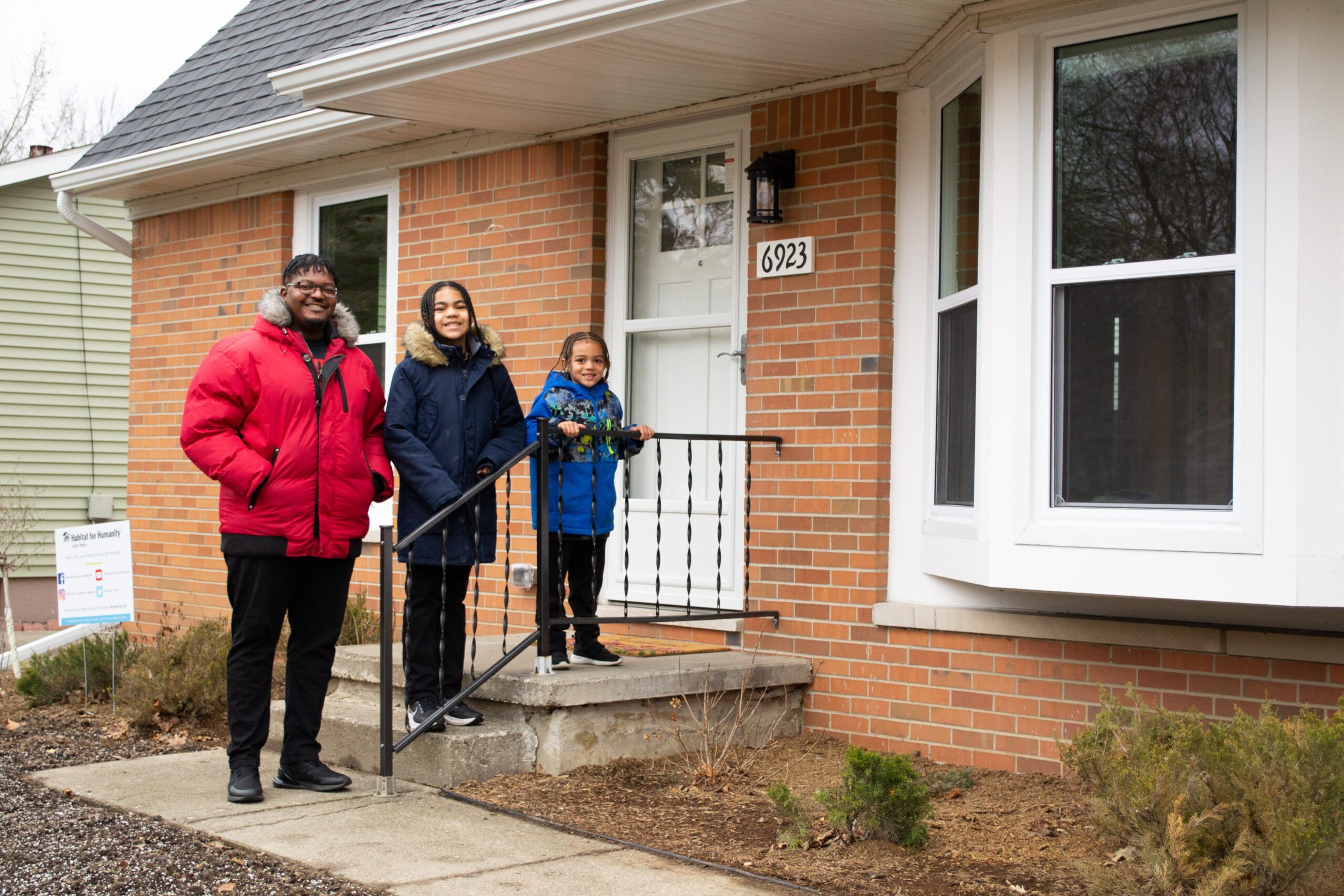 HOS_De'Angelo_Family_Dedication De'Angelo and his sons, Jeadyn and Jordan, stand together on the frint steps of their new Habitat house.