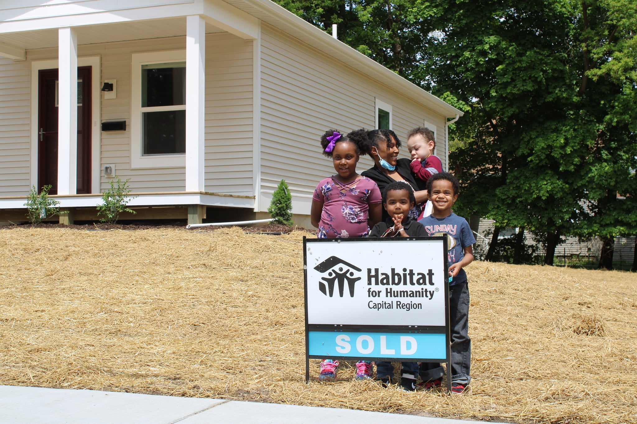 Lonetta and her children smile outside their new Habitat home